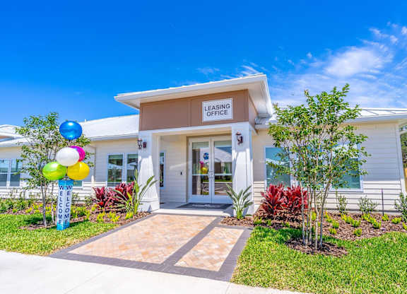 A leasing office building with a sign on the front and colorful balloons to the left.