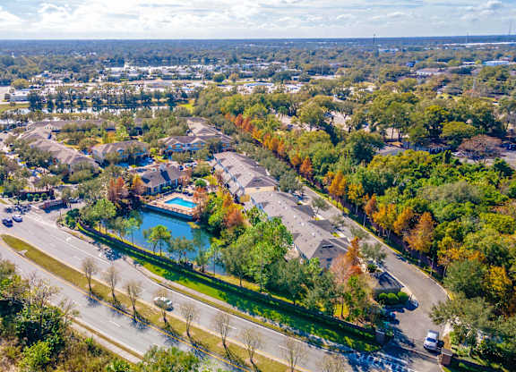 A road with cars and a lake surrounded by trees.