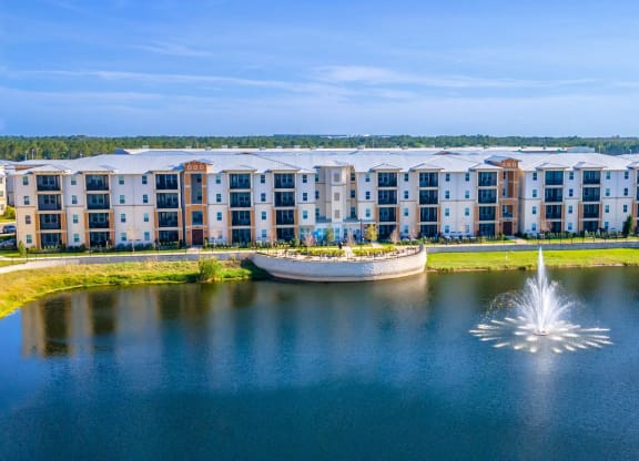 a fountain in the middle of a lake with an apartment building in the background