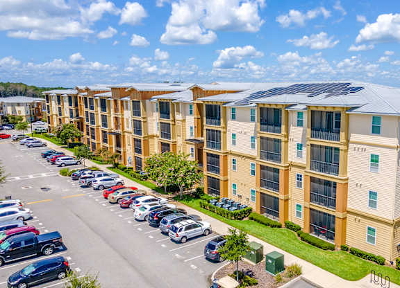 A large apartment complex with a parking lot in front.
