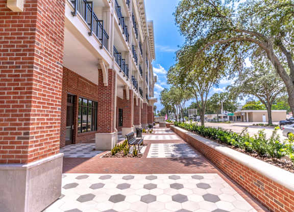 A long brick building with a white and black tiled walkway in front.