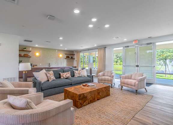 A living room with a grey couch, two armchairs, a coffee table, and a lamp.