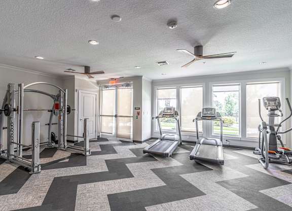 A spacious gym with a variety of equipment including treadmills, elliptical machines, and weightlifting machines.