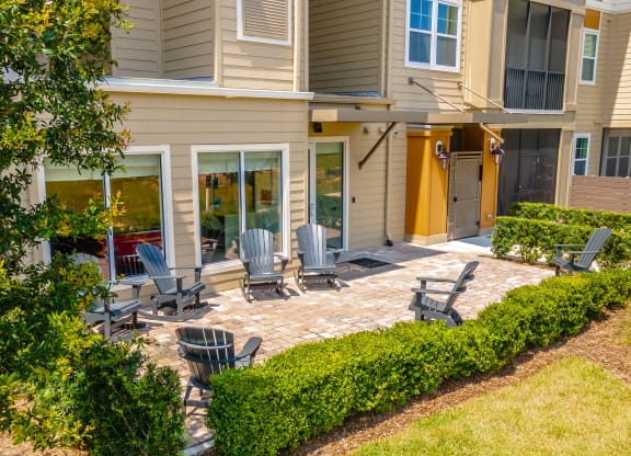 a patio with chairs and a firepit in front of a house