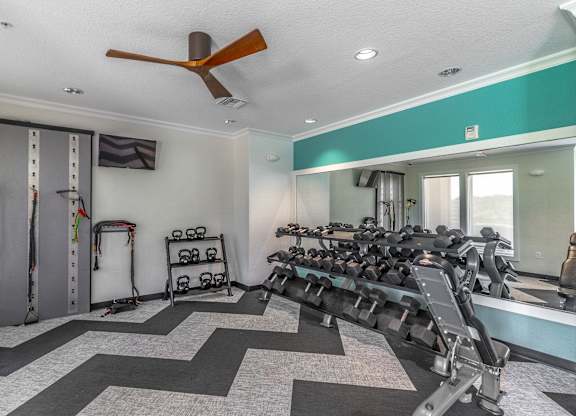 A gym with a row of treadmills and weights.