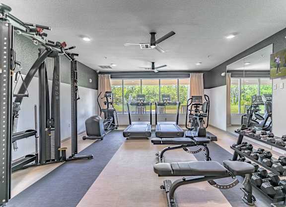 A spacious gym with a variety of equipment including treadmills, weights, and a bench press.