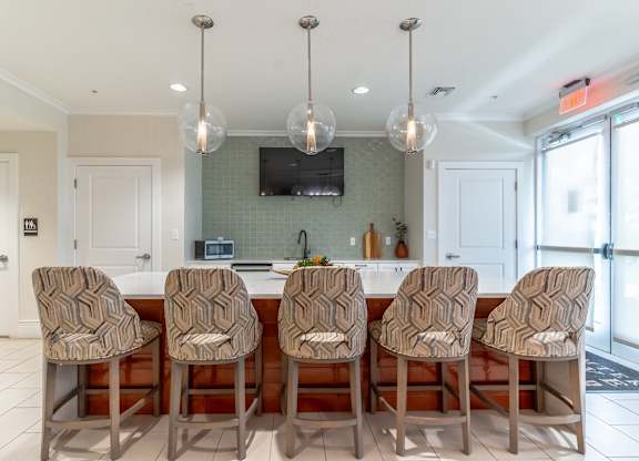 A kitchen with a row of chairs in front of a counter.