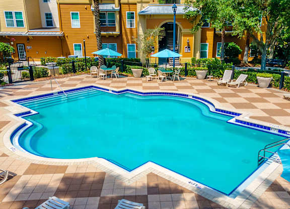 A large outdoor swimming pool surrounded by lounge chairs and umbrellas.