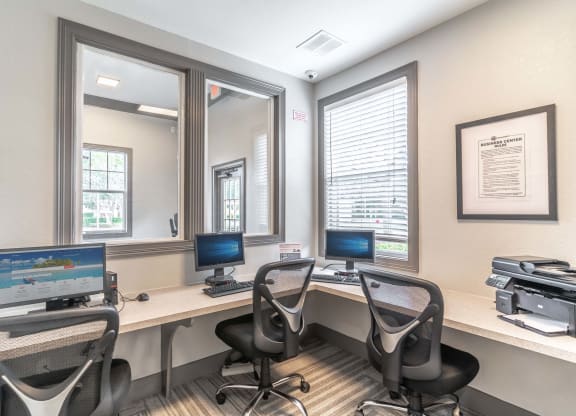 three computer desks in a room with chairs and a printer