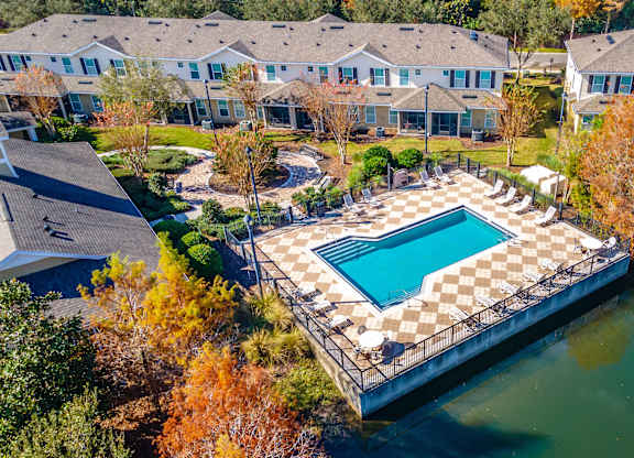 An aerial view of a pool surrounded by a fence and trees.