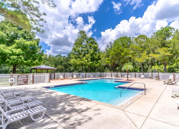 a swimming pool with chairs and a fence around it