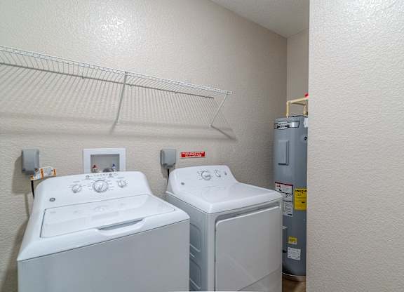 Two white front loading washing machines in a small laundry room.