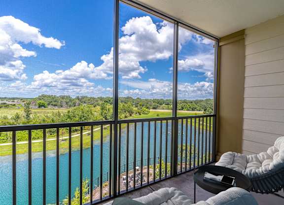 A balcony with a chair and table overlooking a body of water.