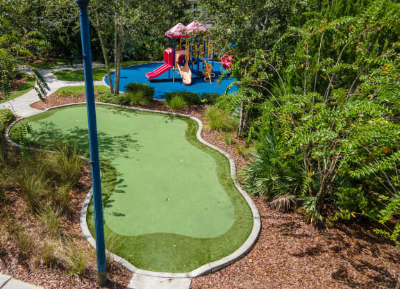 a putting green with a swing in the background