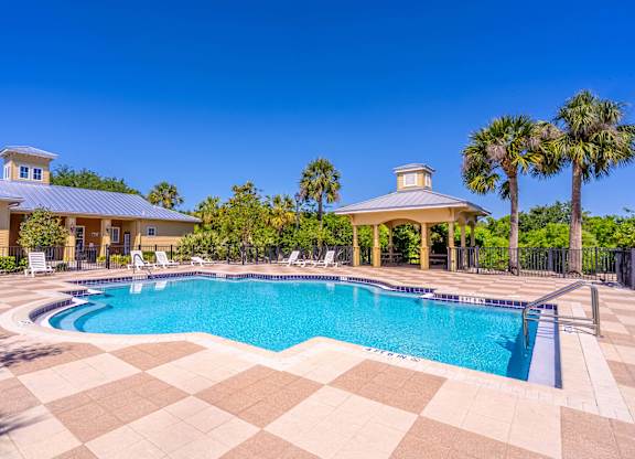 A large swimming pool with a checkered floor and a gazebo in the background.