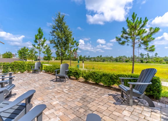a patio with chairs and trees in the background