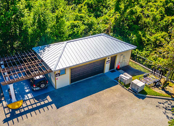 A building with a metal roof and a parking lot in front of it.