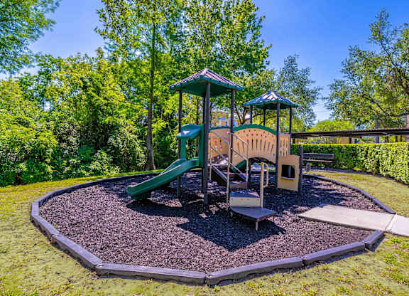 A playground with a green slide and a wooden structure.