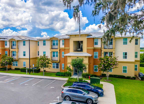 A large apartment complex with a parking lot in front.