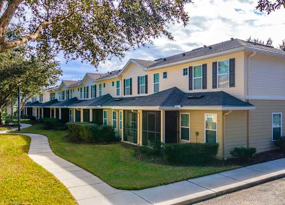 A row of houses with green bushes in front.