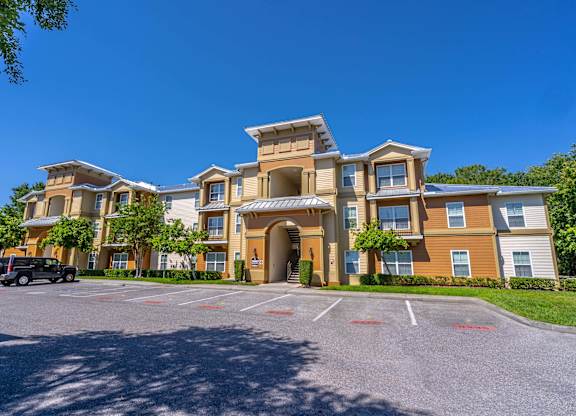 A large, multi-story apartment building with a parking lot in front.