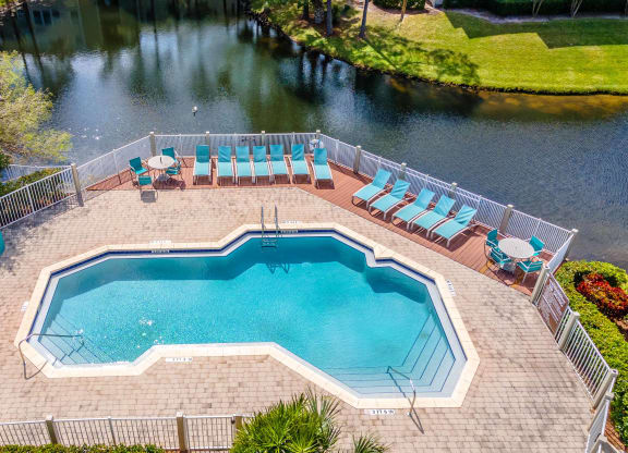 an aerial view of a swimming pool and patio with chairs
