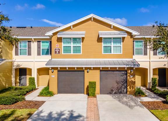 A yellow house with a garage door and a driveway.