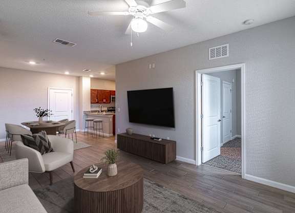 A living room with a television, a sofa, a coffee table, and a ceiling fan.