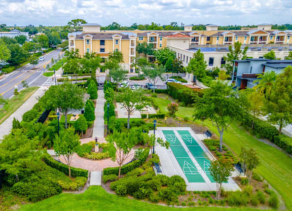 A view of a green garden and shuffleboard area with a building in the background.