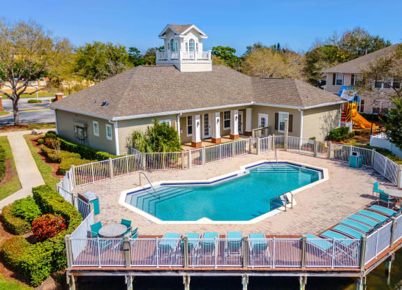 a large pool in front of a house with a deck and a pool house