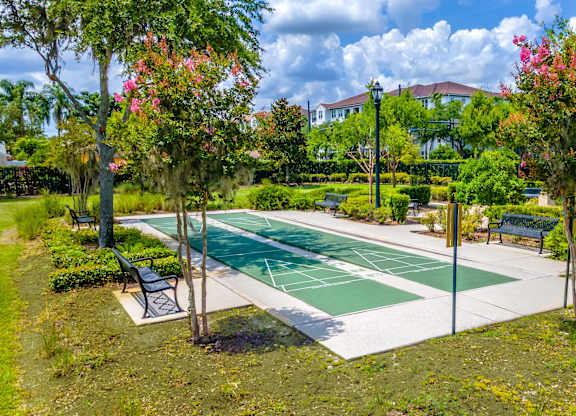 A shuffleboard court surrounded by trees and benches.