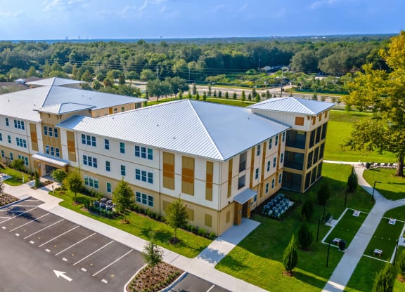 an aerial view of a large building with a parking lot and trees