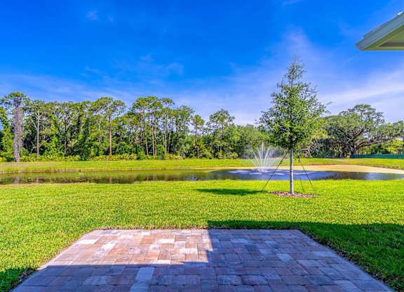 A brick walkway leads to a fountain in a grassy area.