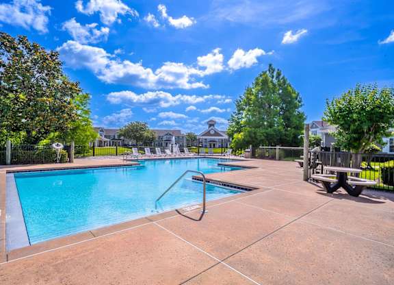 A large outdoor swimming pool surrounded by a fence and trees.