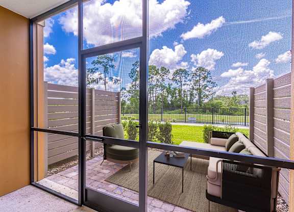 A balcony with a table and chairs overlooking a green lawn.