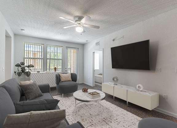 A living room with a grey couch, a white coffee table, and a flat screen TV mounted on the wall.