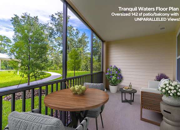 A balcony with a table and chairs overlooking a green lawn.