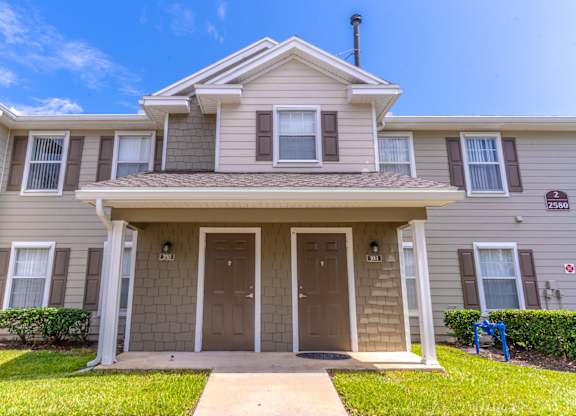 A two-story house with a front porch and a brown door.
