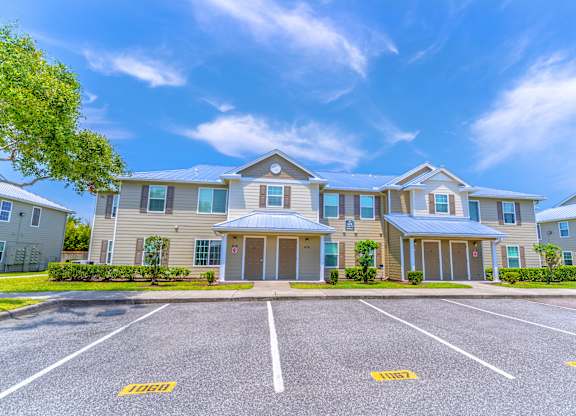 A large apartment complex with a parking lot in front.