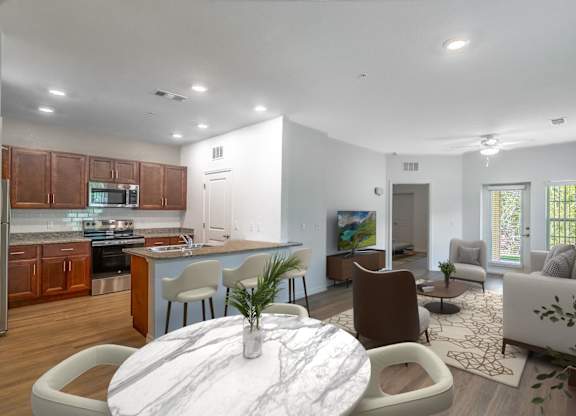 A modern living room with a white marble coffee table and a kitchen area in the background.
