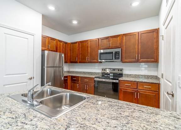 A kitchen with granite countertops and wooden cabinets.