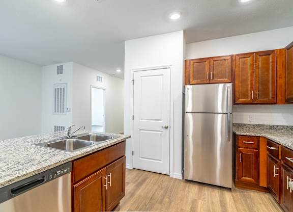 A kitchen with a stainless steel refrigerator and wooden cabinets.