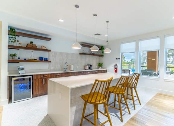 A kitchen with a white island and wooden chairs.