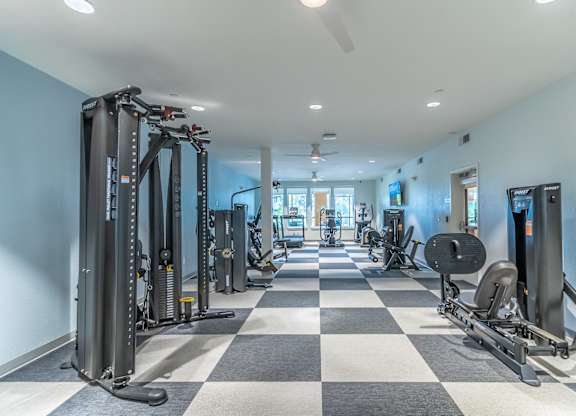 A spacious gym with a variety of equipment including treadmills, weight machines, and free weights.