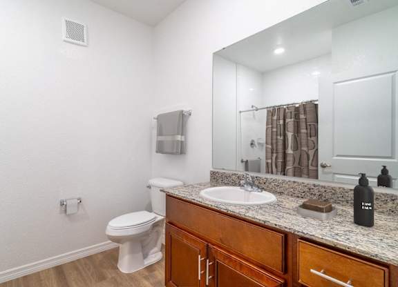 A bathroom with a toilet, sink, and mirror.