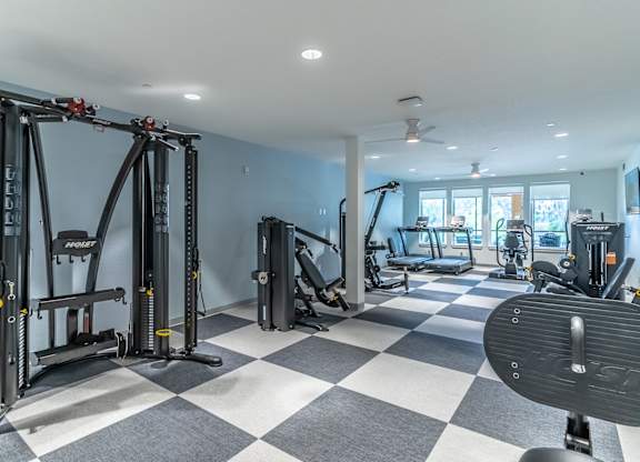 A gym with a variety of equipment including a squat rack, bench press, and a barbell.
