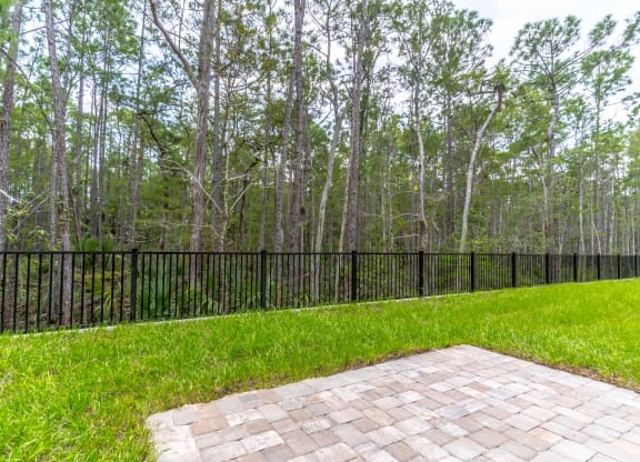 the backyard has a brick patio and a black fence