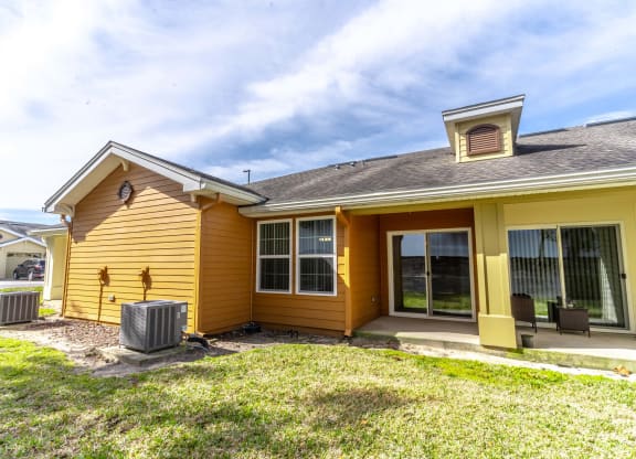the front of a yellow house with a yard and grass