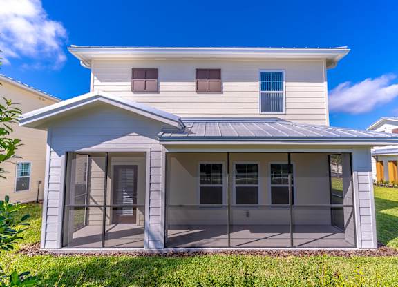 A modern house with a grey roof and a glass door.