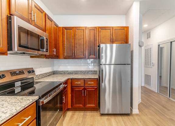 A kitchen with wooden cabinets and a stainless steel refrigerator.